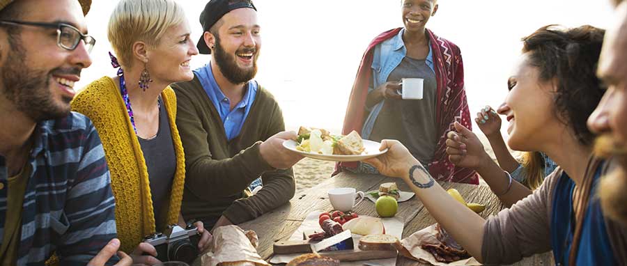 Sober friends eat together on the beach while in drug rehab