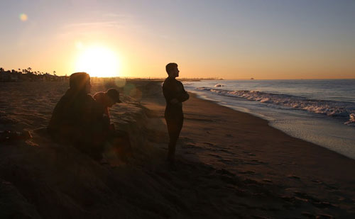 Men on beach at sunrise