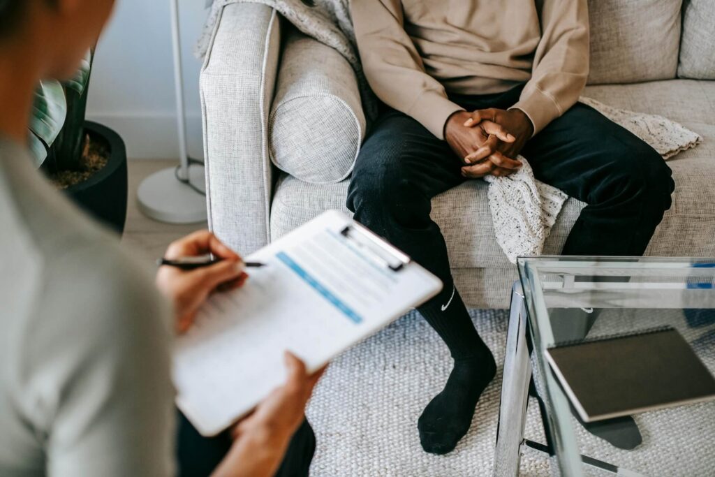 A man in a tan sweater talking to a doctor while attending rehab in California.